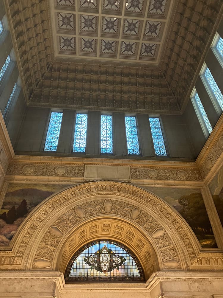 非常に背の高いホールの壁と天井を下から撮った写真。全体的に細かい彫刻が施され、絵やステンドグラスもある。