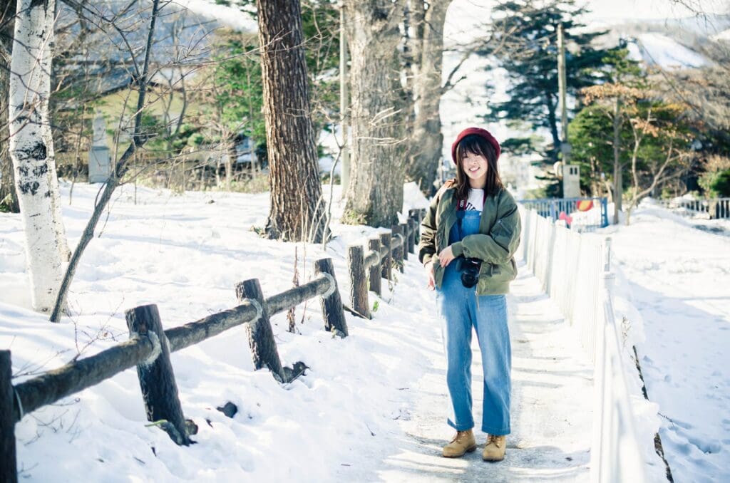 カメラを持っている女性が雪道に立っています。