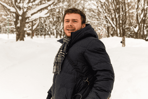 アメリカ人スタッフのジャスティンが雪が降り積もった森の中に立っています。