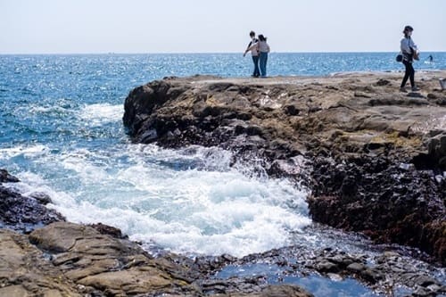 海にせり出たいわばに2人立っている