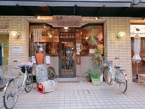 カフェの入り口。植物や自転車が置かれている。