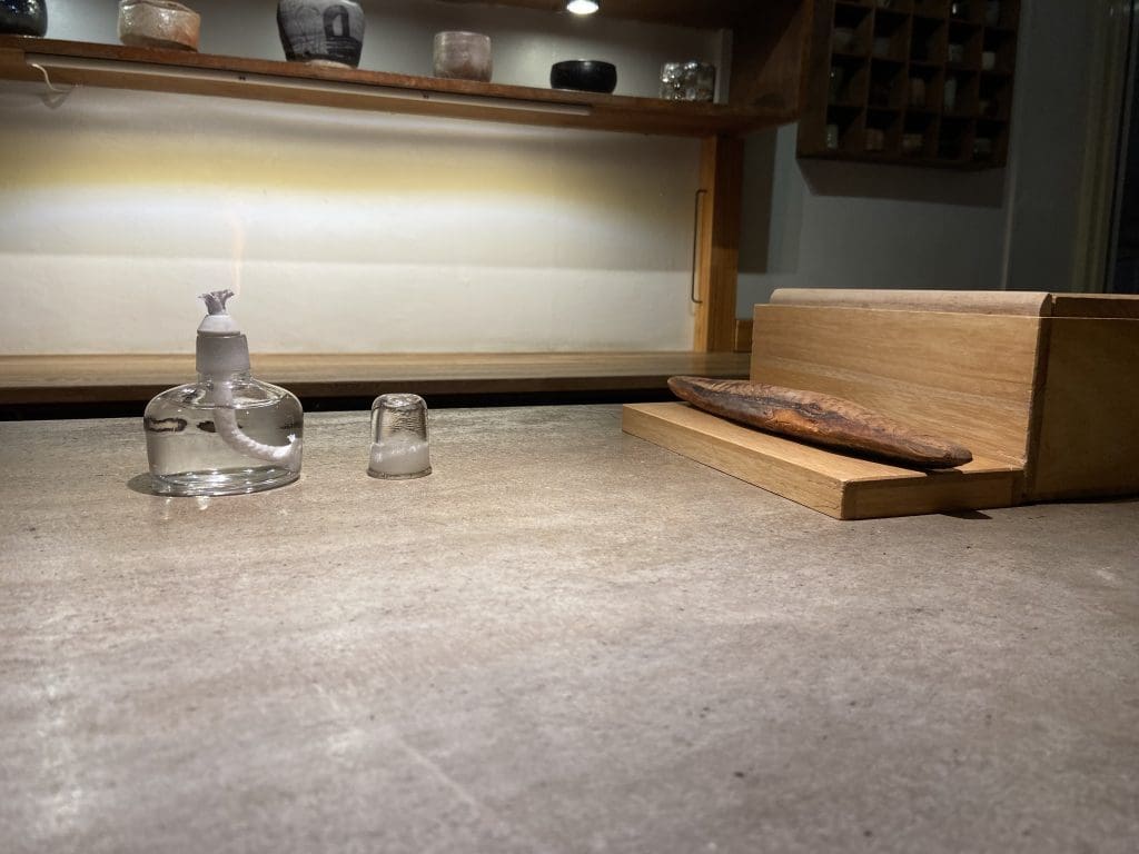 カウンターの上に、鰹節を炙るためのアルコールランプ、横には鰹節と鰹節を削るための削り器があります。