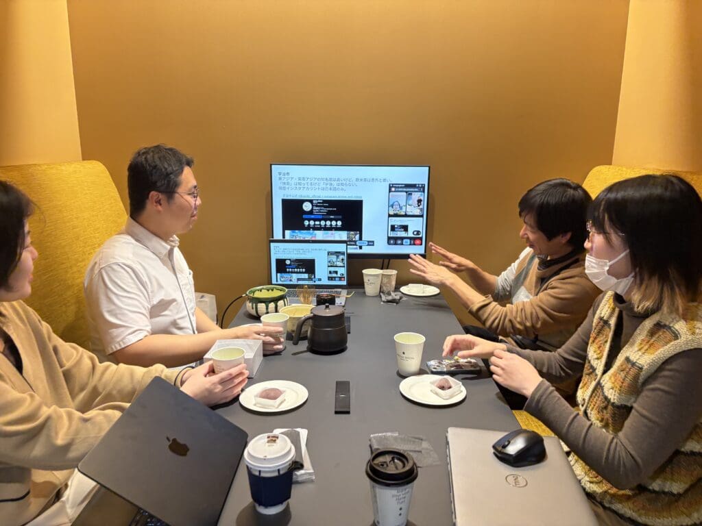 モニターの前に4人の社員がすわって、薄茶と和菓子を楽しんでいます。