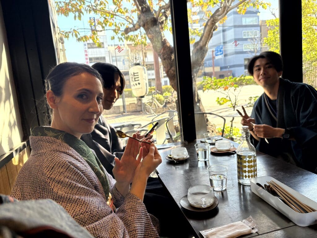 背景に窓があり、手前に3人がランチを食べる様子です。