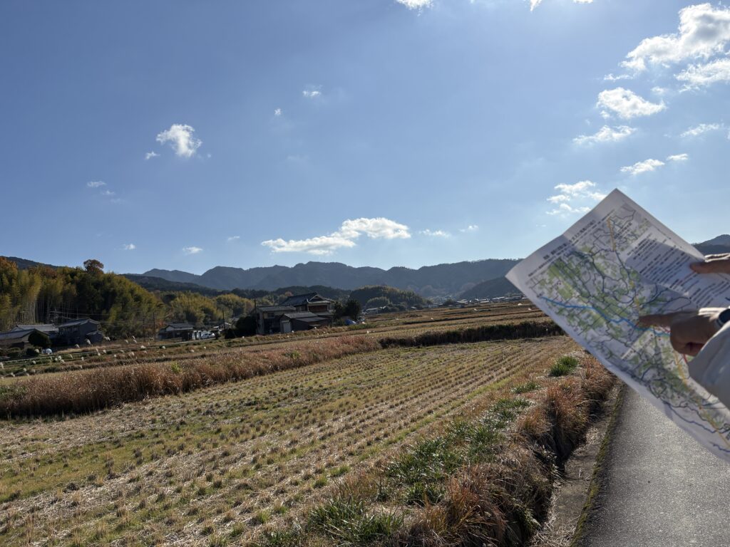 稲を刈ったあとの田園風景と右の端には地図を持った人