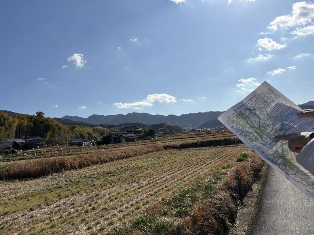 稲を刈ったあとの田園風景と右の端には地図を持った人