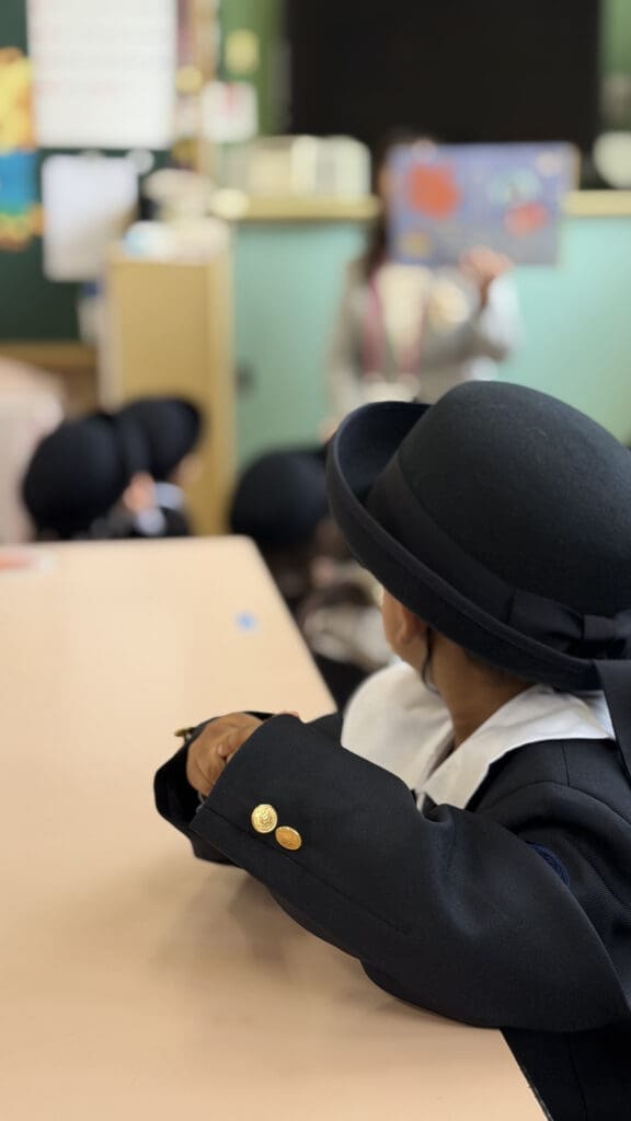 Izaan is sitting on the chair and following his teacher.