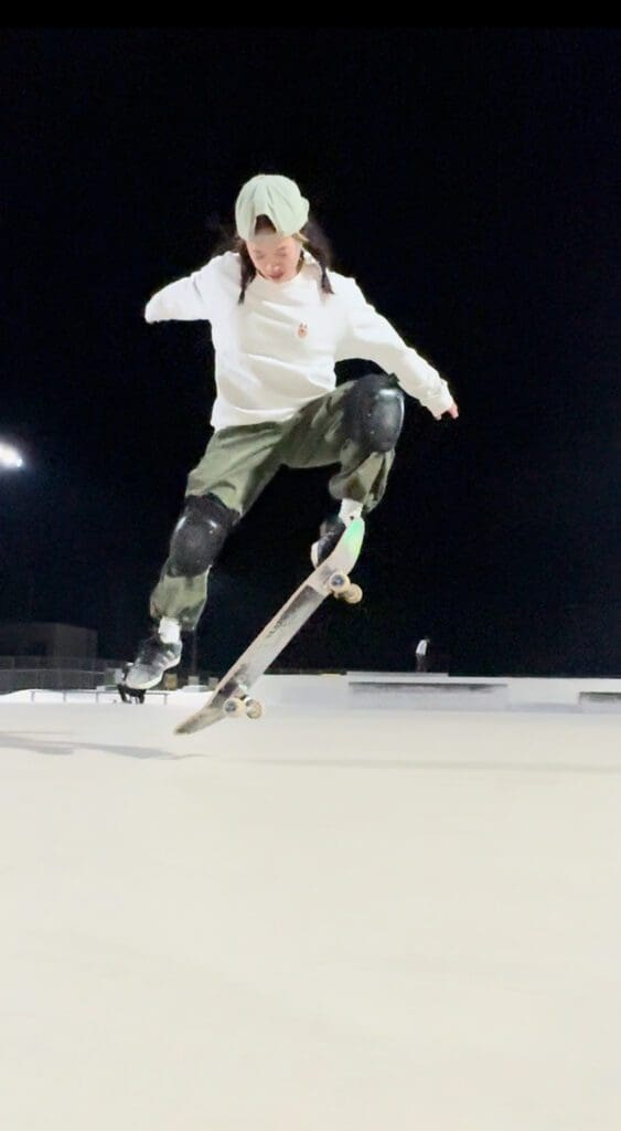 夜にスケートパークでオーリーを練習している女性です。