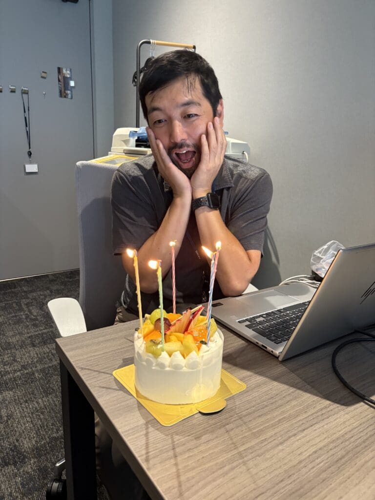 バースデーケーキを前に両手をほほにおいて「わー!」と役員が喜んでいる。