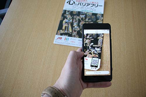 チラシに付いているQRコードをスマートフォンで読み取っている画像