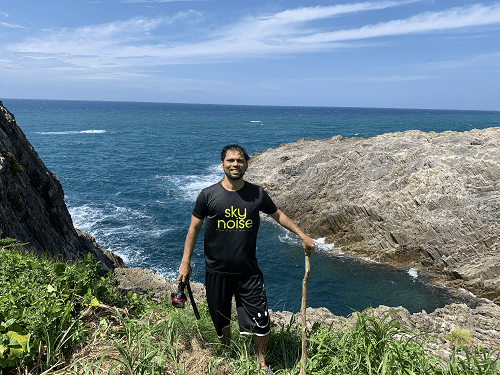 越前海岸の崖の上で海を背景にたっているアミンです。