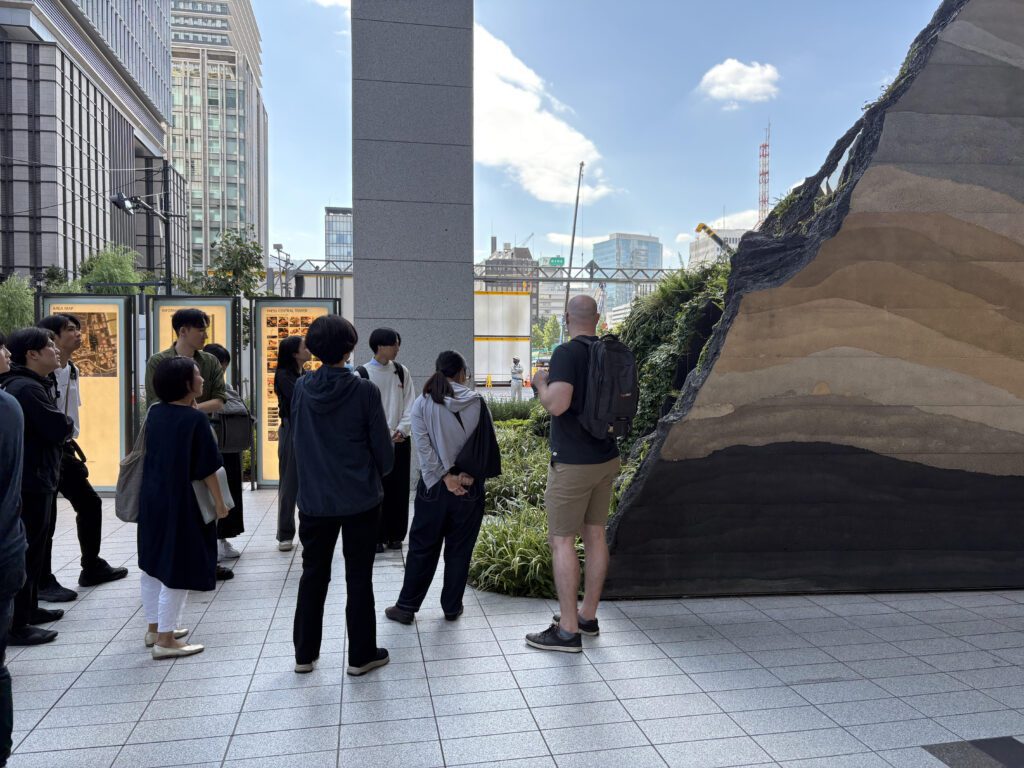 ビルの1階に設置された地層が見える作品の前で複数の人が鑑賞しています。