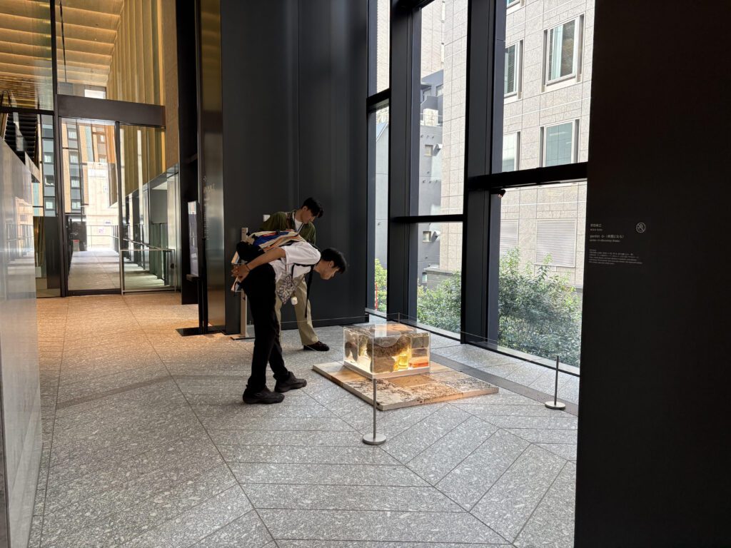 床に設置された作品を2人の男性が鑑賞しています。