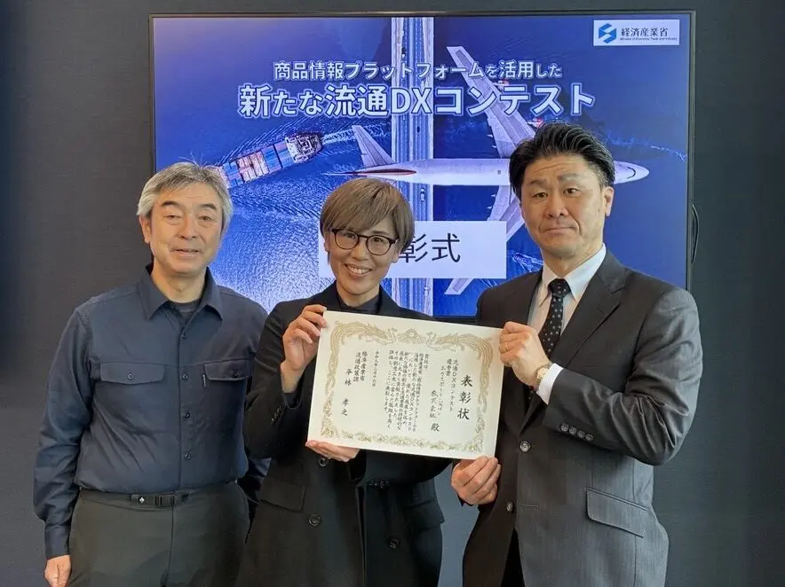 流通DX表彰式で賞状を掲げての記念撮影3名の人物が映っている