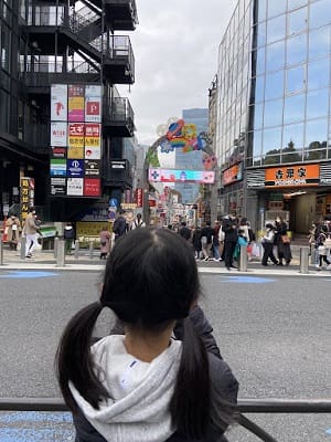 竹下通りの入り口にカメラを向けている娘さんの後ろ姿。