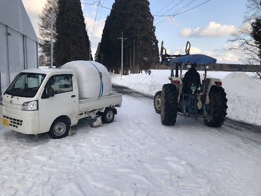 餌のロールを積んだ軽トラとトラクター