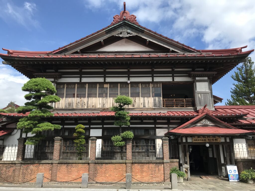 太宰治の実家「斜陽館」の外観。壮大な二階建て和風建築物。屋根は鮮やかな赤色。