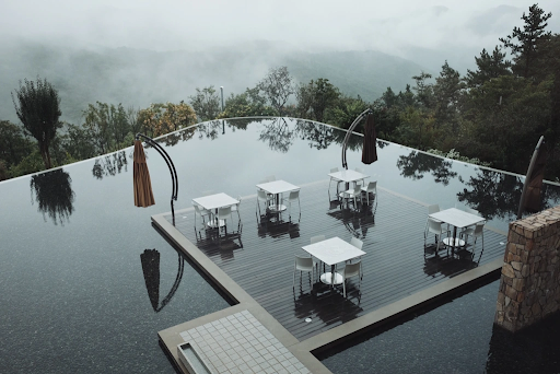 霧が立ち込める渓谷の上に建てられてたカフェテラス。白いテーブルと椅子が写っている。